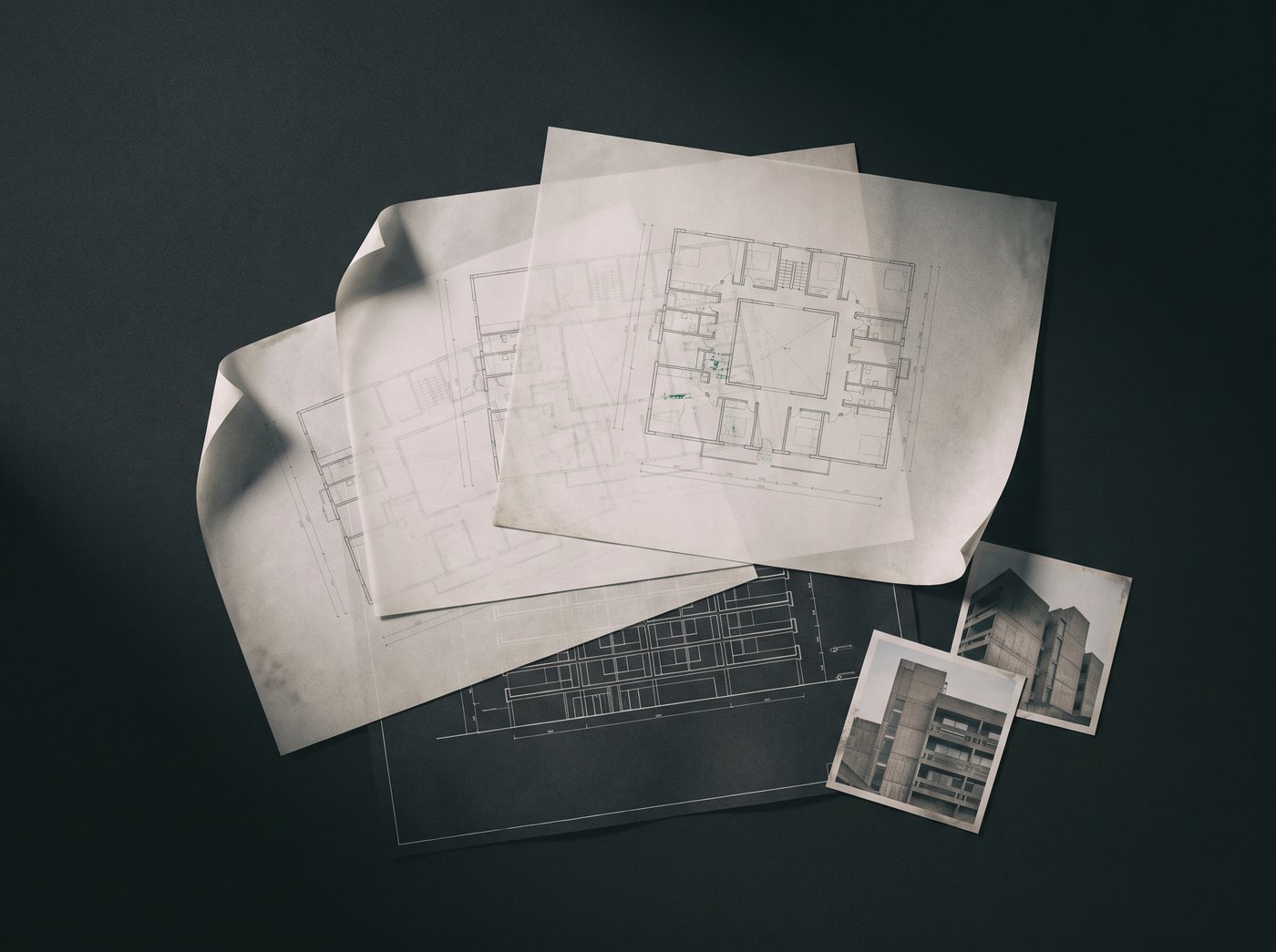 Architectural floor plans, an elevation drawing and facade reference prints on a dark surface.